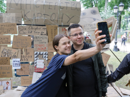 Jaunieši Kijivā pozē pie simboliskas sienas ar plakātiem, kuri tika izmantoti protestos pret pretkorupcijas iestāžu neatkarības likvidēšanu.