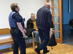 Lato Lapsa un Mihails Uļmans (ar muguru) Mārtiņa Bunkus slepkavības tiesas sēdes pārtraukumā pagājušā gada februārī,