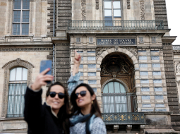 Tūristes pie izsistā loga, pa kuru laupītāji iekļuva Luvras muzejā.