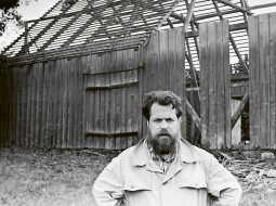Juris Kunnoss pie nojaucama šķūņa-rijas toreizējā Āronas ciema padomes teritorijā Madonas rajonā. 1986. gads.
Fotogrāfs — nezināms. Etnogrāfiskā brīvdabas muzeja krājums