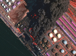 No satelīta uzņēmtā attēlā redzams plašs ugunsgrēks Ustjugas ostā 27. martā.